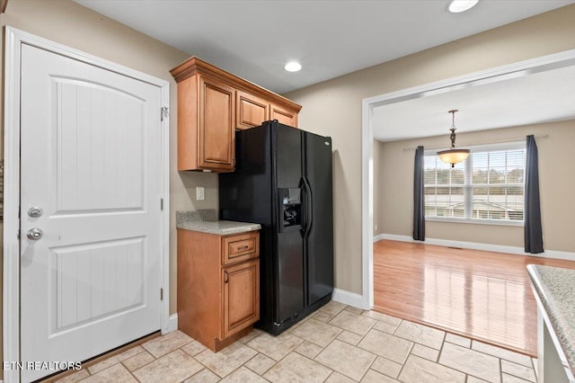 kitchen with decorative light fixtures, black fridge with ice dispenser, and light wood-type flooring