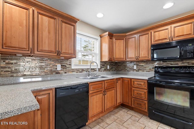 kitchen featuring backsplash, light stone counters, sink, and black appliances