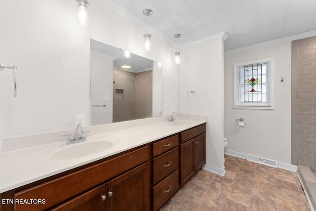 bathroom featuring a tile shower, vanity, ornamental molding, and toilet