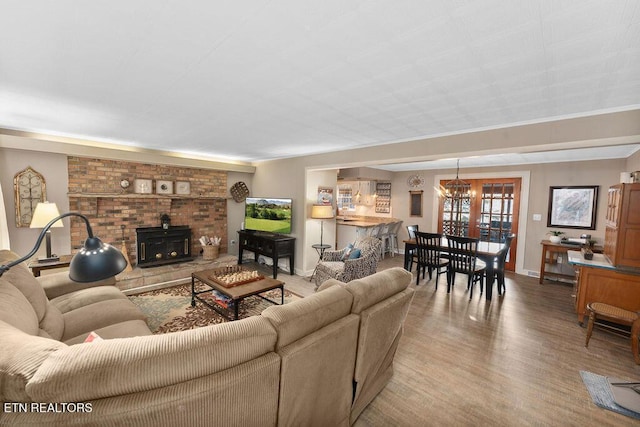 living room with hardwood / wood-style floors, an inviting chandelier, and a wood stove