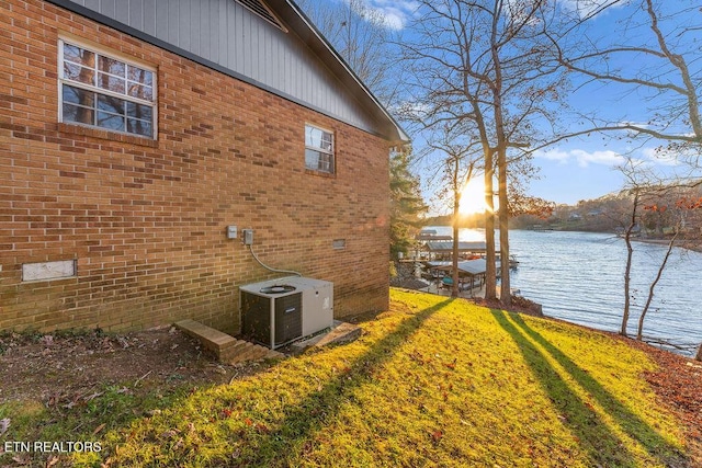 view of property exterior with a water view, a yard, and central AC