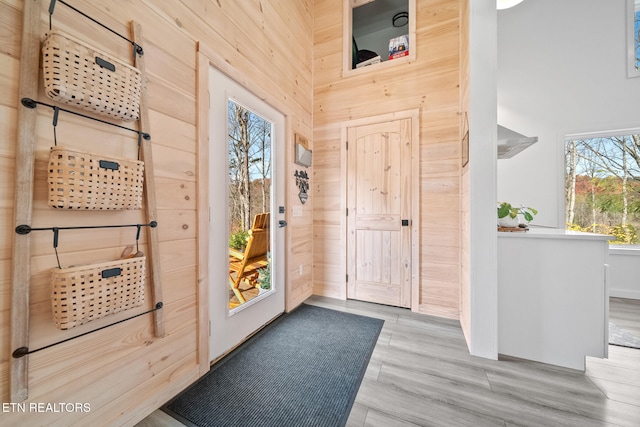 entrance foyer with wooden walls, light hardwood / wood-style flooring, and a high ceiling