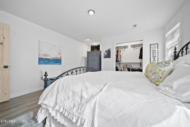 bedroom featuring hardwood / wood-style flooring, a walk in closet, and a closet