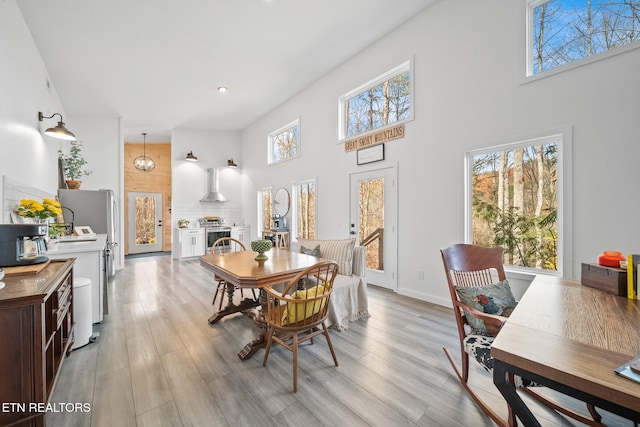 dining area with light wood-type flooring and a towering ceiling