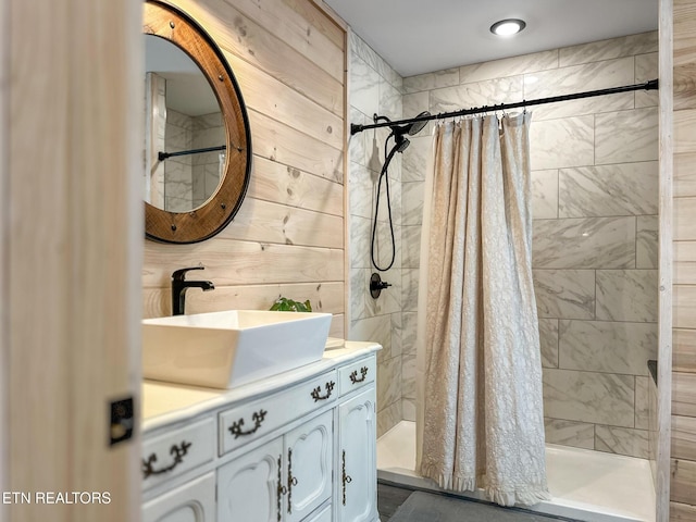 bathroom with a shower with curtain, vanity, and wooden walls