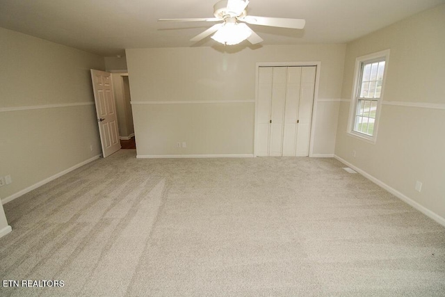 unfurnished bedroom featuring ceiling fan, a closet, and light carpet