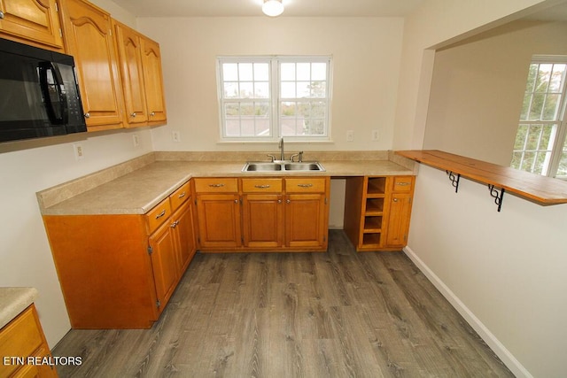 kitchen with kitchen peninsula, a wealth of natural light, sink, and dark wood-type flooring