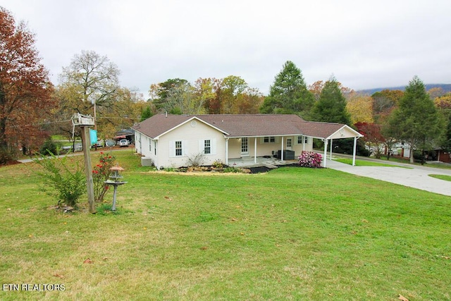 ranch-style house with a front yard, central air condition unit, a carport, and covered porch