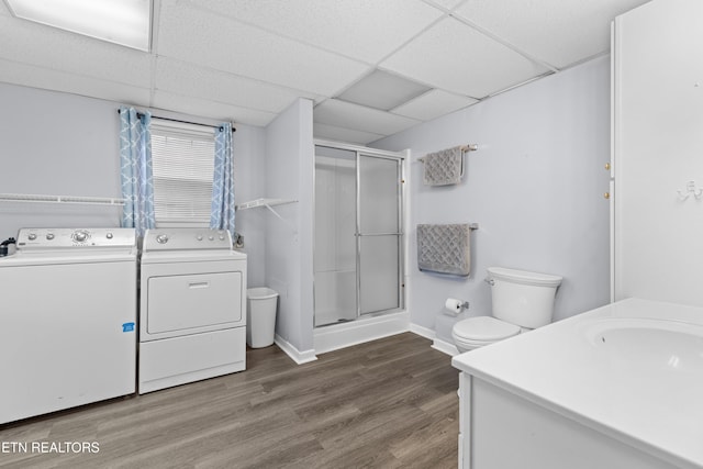 bathroom with a drop ceiling, washing machine and dryer, vanity, a shower with shower door, and hardwood / wood-style flooring