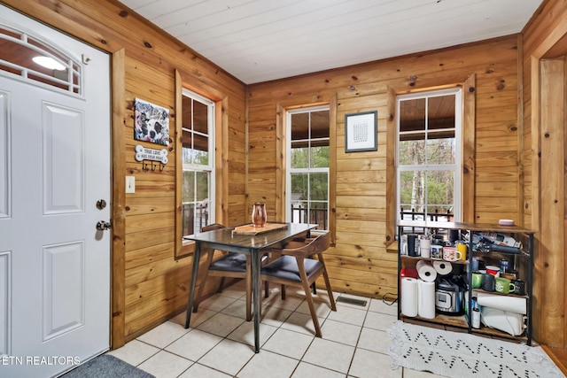 tiled dining room featuring wooden walls