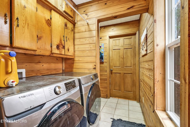 laundry area with washing machine and dryer, wooden walls, light tile patterned flooring, and cabinets