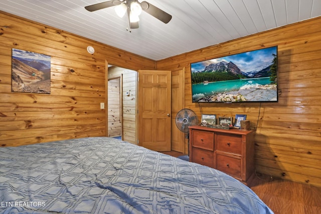 bedroom featuring hardwood / wood-style floors, ceiling fan, and wooden walls