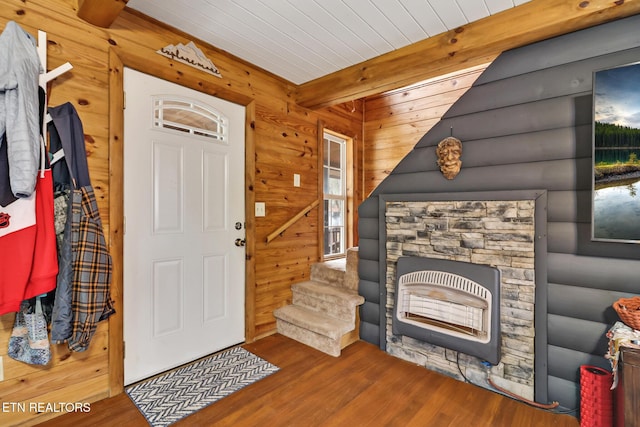 foyer featuring heating unit, wooden walls, hardwood / wood-style floors, and beamed ceiling