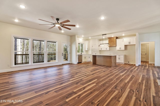 unfurnished living room featuring ceiling fan, dark hardwood / wood-style flooring, and sink