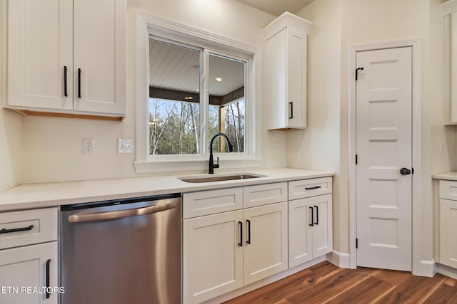 kitchen with white cabinets, dishwasher, sink, dark hardwood / wood-style floors, and light stone counters