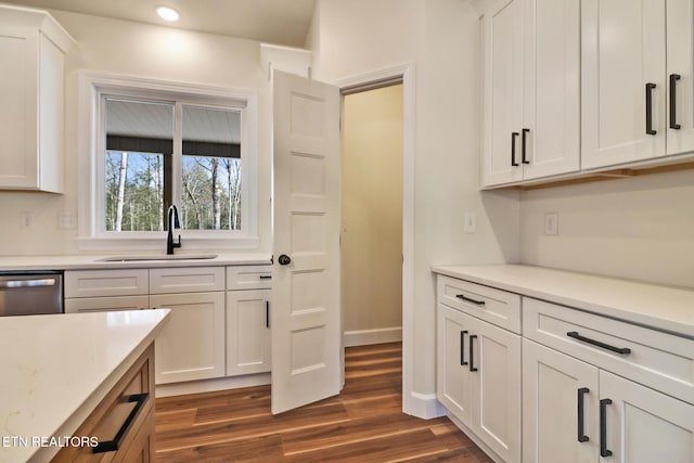 kitchen featuring dark wood-type flooring, white cabinetry, stainless steel dishwasher, and sink