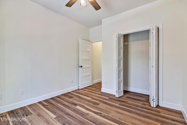 unfurnished bedroom with ceiling fan, dark wood-type flooring, and a closet