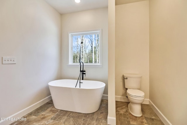 bathroom featuring toilet and a washtub