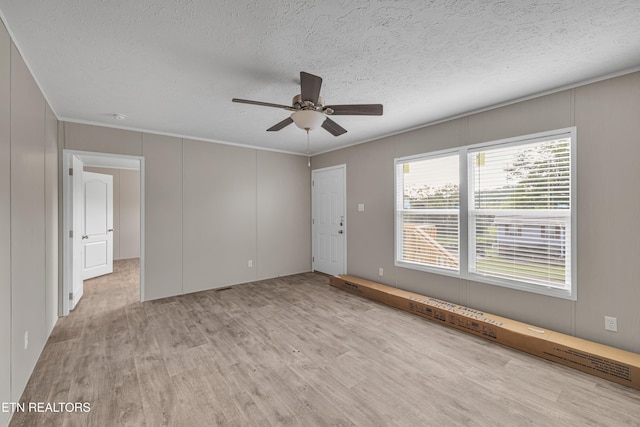 empty room with a textured ceiling, light hardwood / wood-style floors, ceiling fan, and crown molding