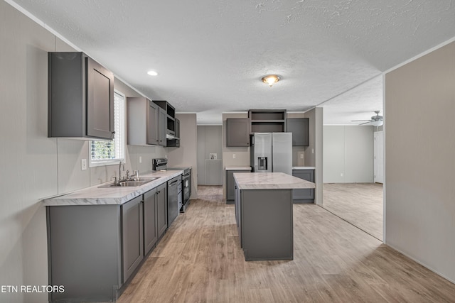 kitchen with gray cabinetry, a center island, light hardwood / wood-style floors, and appliances with stainless steel finishes