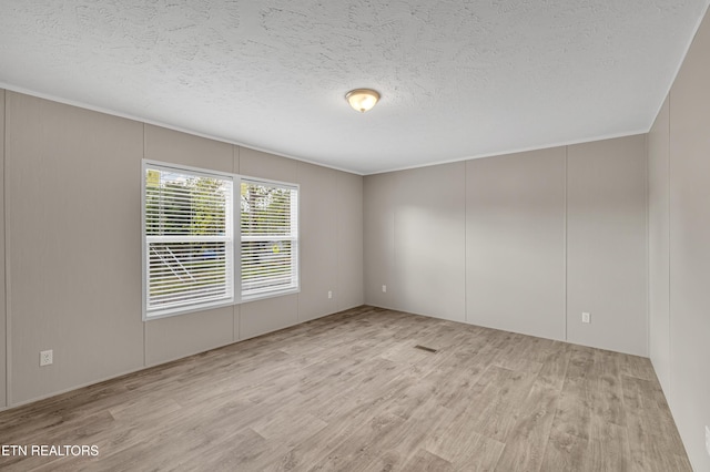 unfurnished room with crown molding, a textured ceiling, and light wood-type flooring