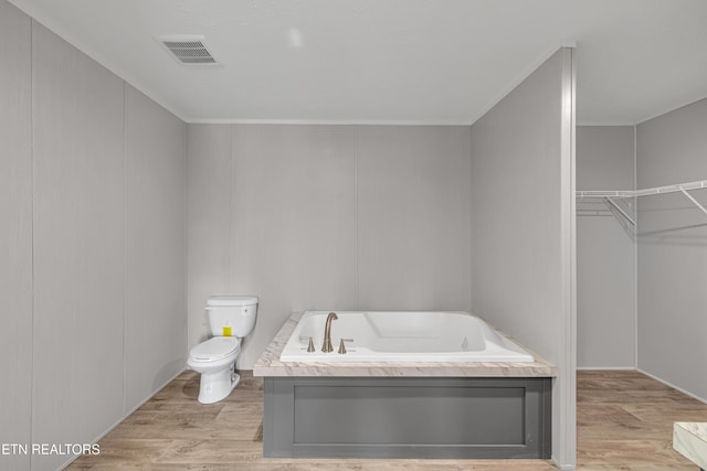 bathroom featuring a tub to relax in, wood-type flooring, and toilet