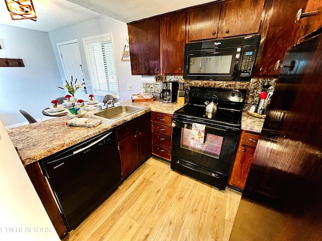 kitchen featuring sink, light wood-type flooring, light stone counters, and black appliances