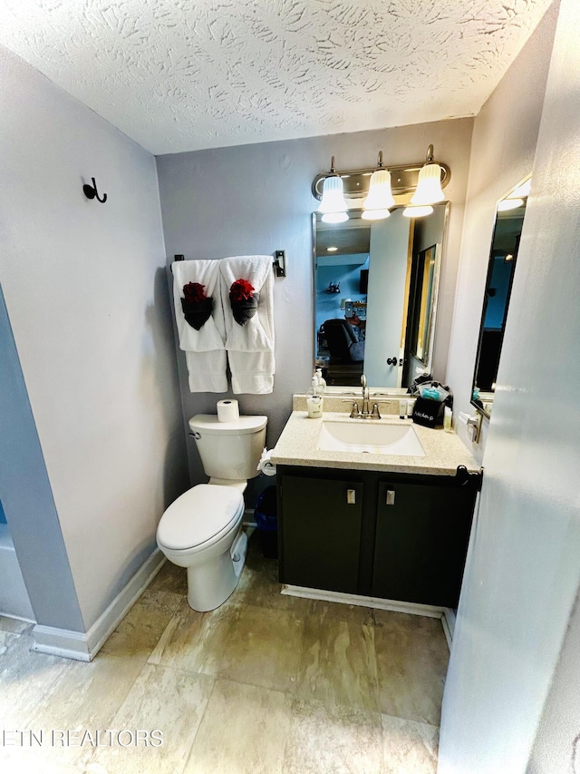 bathroom with vanity, toilet, and a textured ceiling