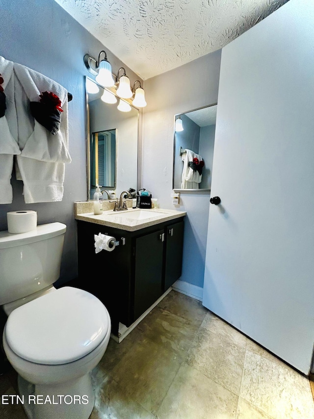 bathroom featuring vanity, a textured ceiling, and toilet