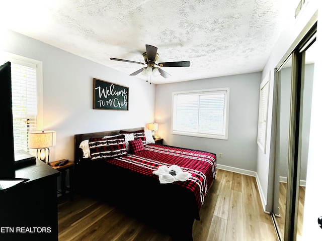 bedroom with ceiling fan, a closet, wood-type flooring, and a textured ceiling