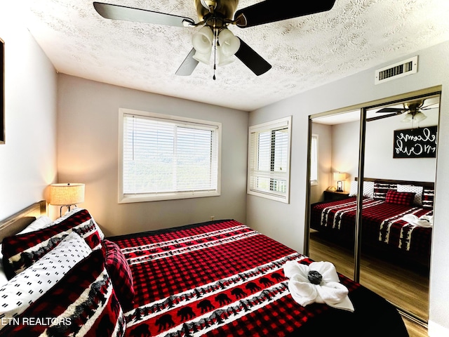 bedroom featuring ceiling fan, a closet, wood-type flooring, and a textured ceiling