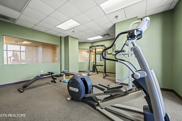 exercise room featuring a paneled ceiling and carpet flooring