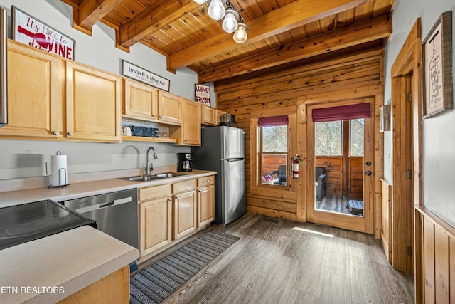 kitchen featuring light brown cabinets, sink, wooden walls, beam ceiling, and stainless steel appliances