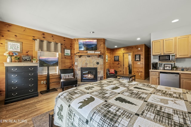 bedroom with a fireplace, light wood-type flooring, and wooden walls