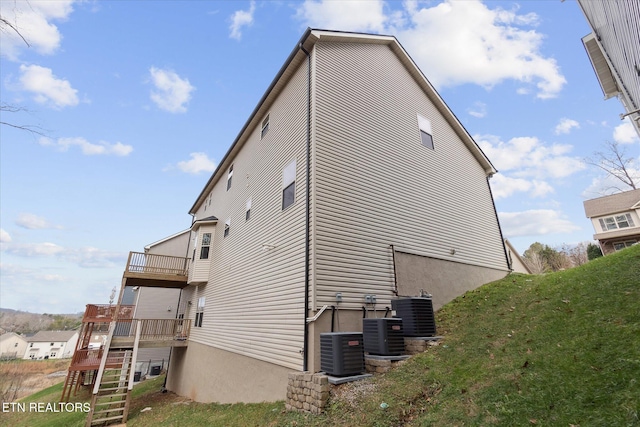 view of home's exterior with central AC unit, a balcony, and a lawn