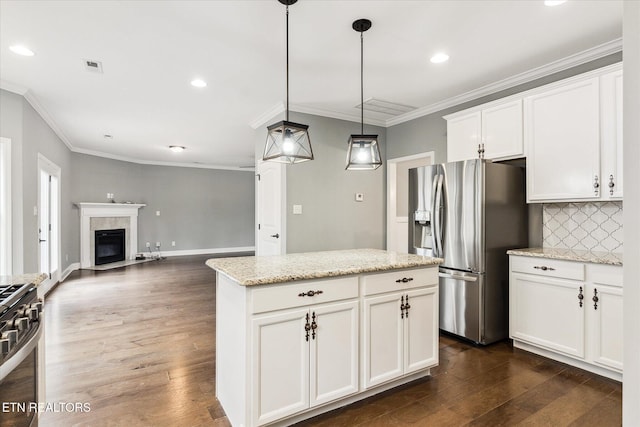 kitchen featuring decorative backsplash, appliances with stainless steel finishes, light stone counters, pendant lighting, and white cabinetry