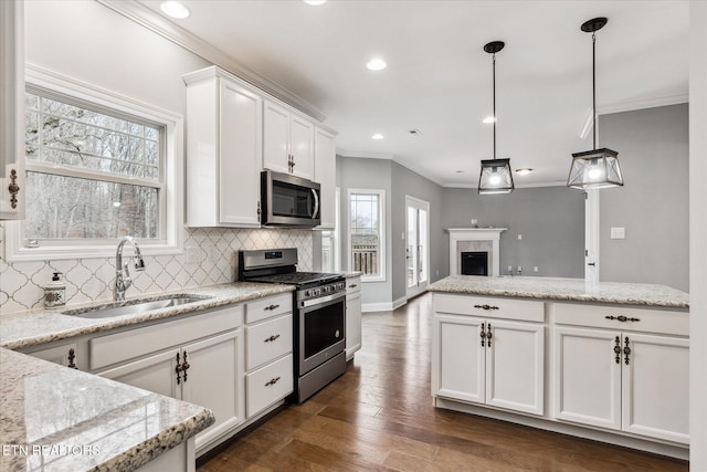 kitchen featuring stainless steel appliances, dark wood-type flooring, sink, white cabinetry, and hanging light fixtures