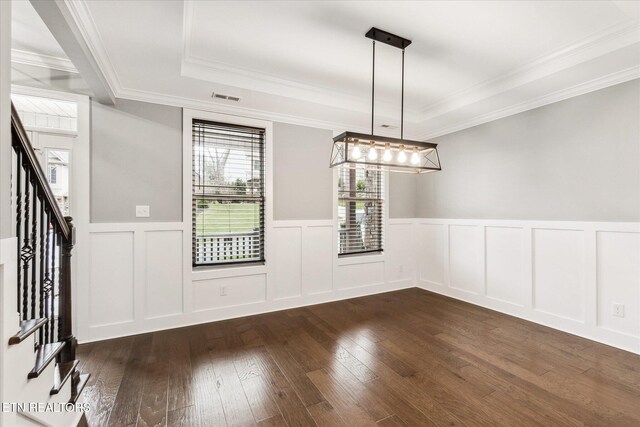 unfurnished dining area featuring dark hardwood / wood-style flooring, a raised ceiling, and crown molding