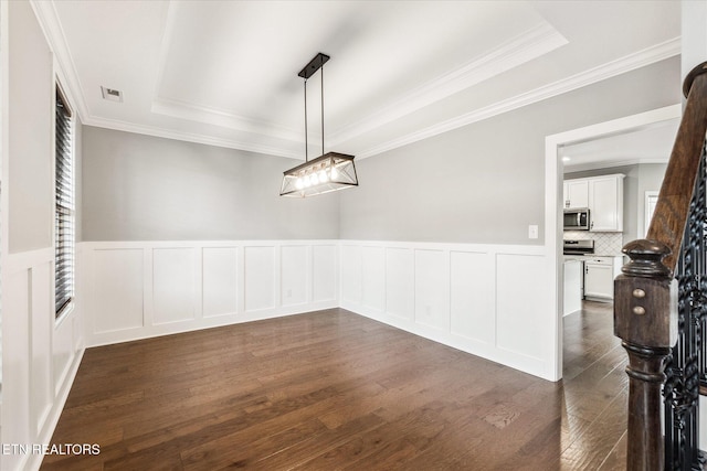 unfurnished dining area featuring dark hardwood / wood-style flooring, a tray ceiling, and crown molding