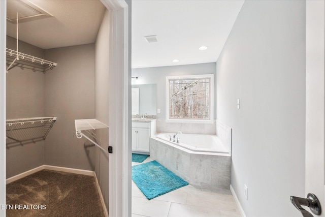 bathroom featuring tile patterned floors, vanity, and tiled bath