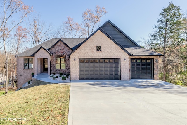 view of front of home with brick siding, a front yard, an attached garage, and driveway