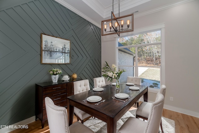 dining space featuring light wood-style flooring, baseboards, a chandelier, and ornamental molding