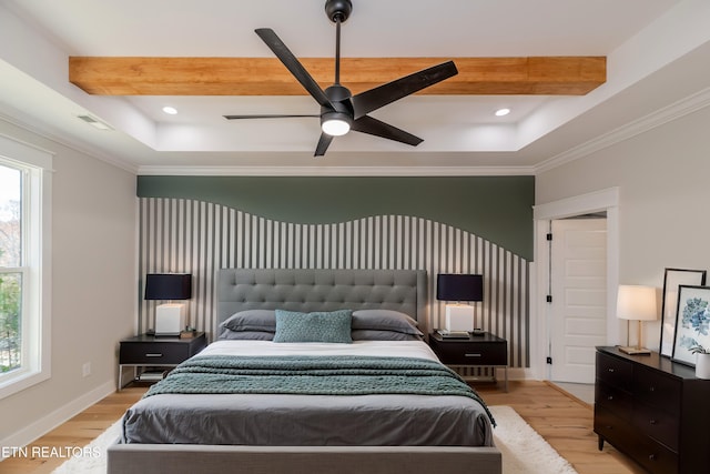 bedroom with a tray ceiling, light wood-type flooring, and multiple windows