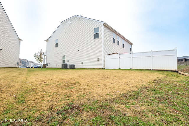 rear view of property featuring a yard and central air condition unit