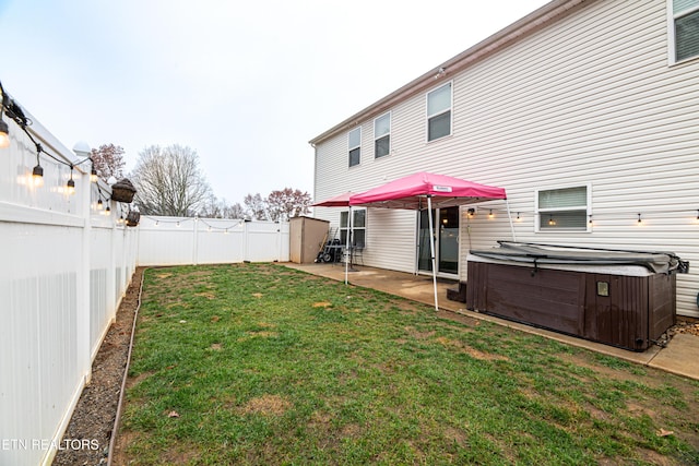 back of property with a hot tub, a patio area, and a lawn