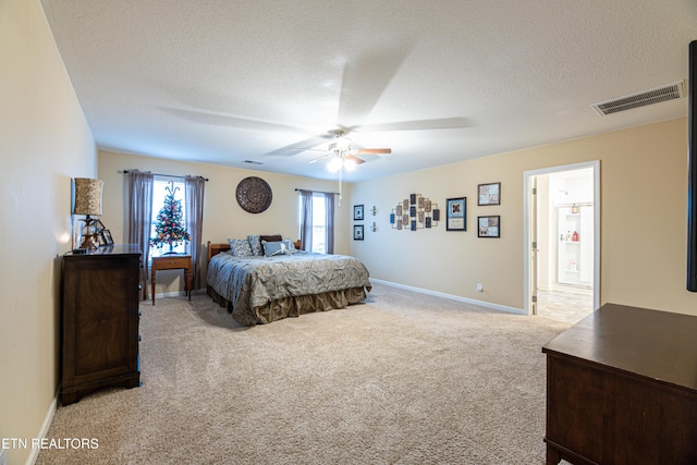 bedroom with light carpet, a textured ceiling, ensuite bathroom, and ceiling fan