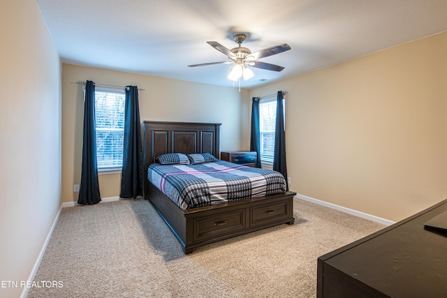 bedroom with light carpet, multiple windows, and ceiling fan