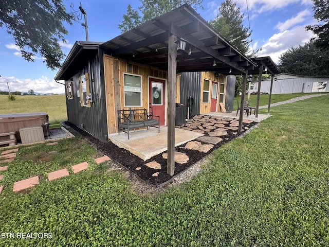 back of property featuring a patio area, a hot tub, and a lawn