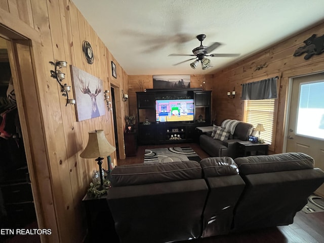 living room featuring ceiling fan and wood walls