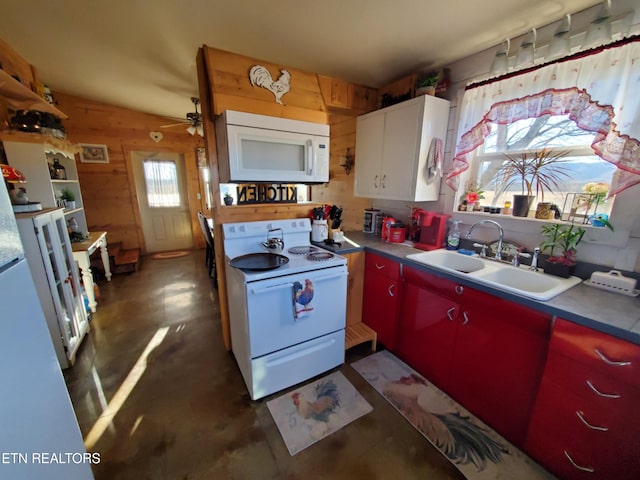 kitchen with a healthy amount of sunlight, sink, wooden walls, and white appliances